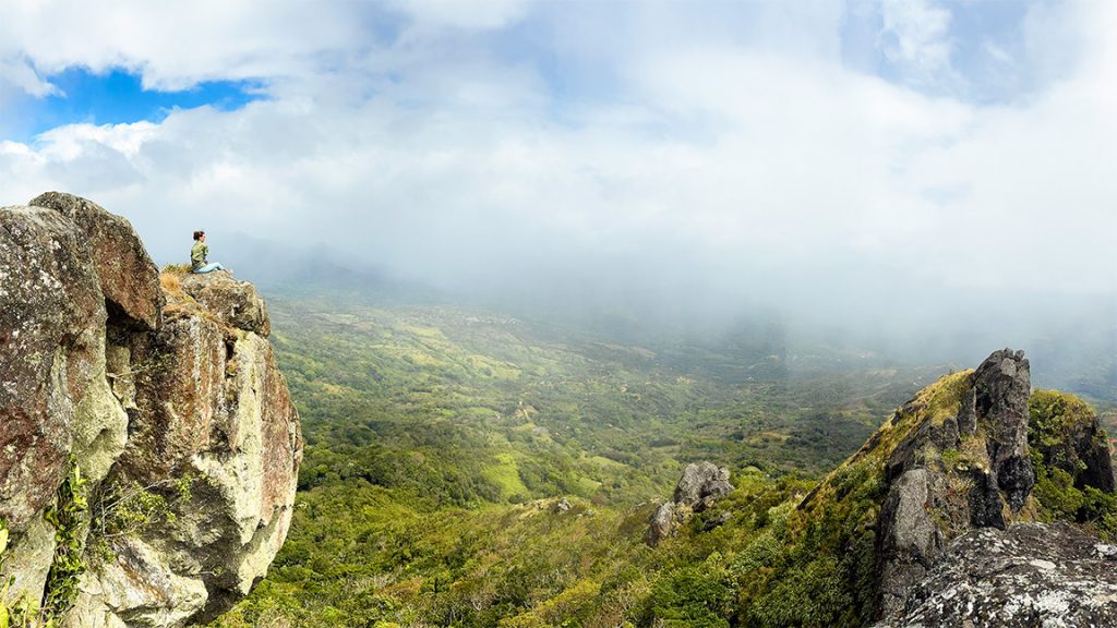 A woman sitting on a rock on the summit of Cerro Tute Hike in Santa Fe Veraguas