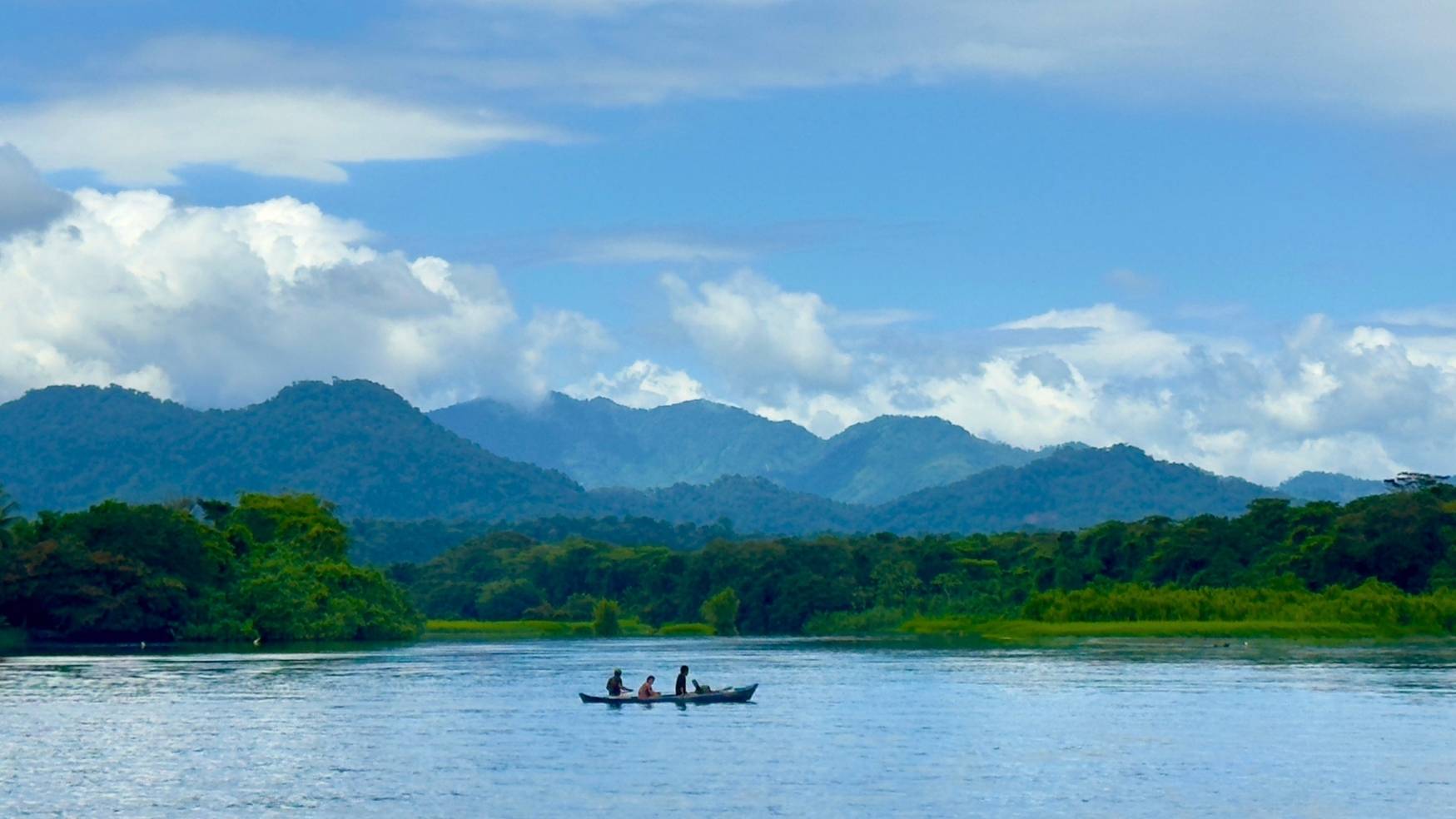 Indigenous family crossing the Calovebora river on a traditional wood canoe