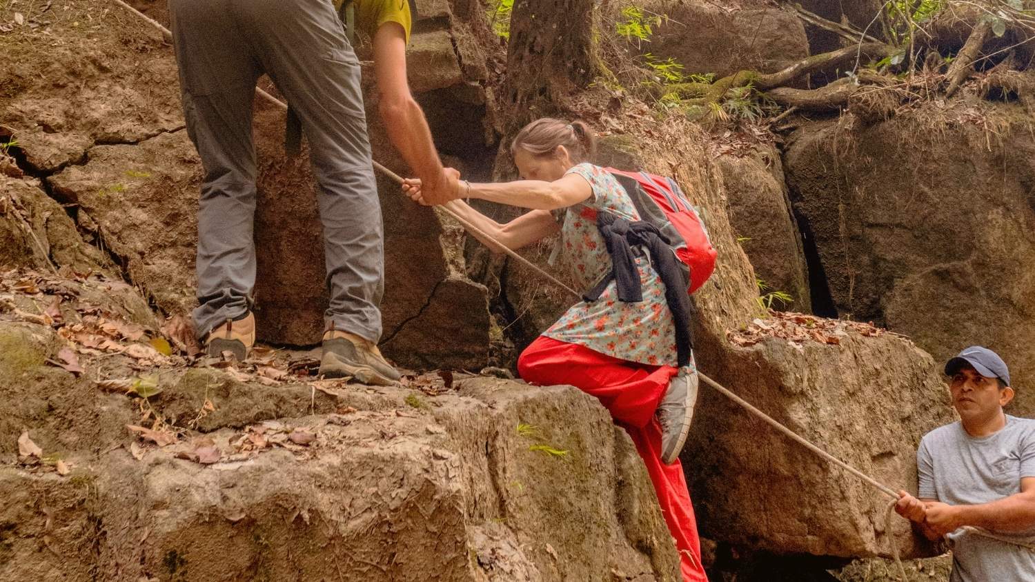 Guide helping a woman climb a rock 1