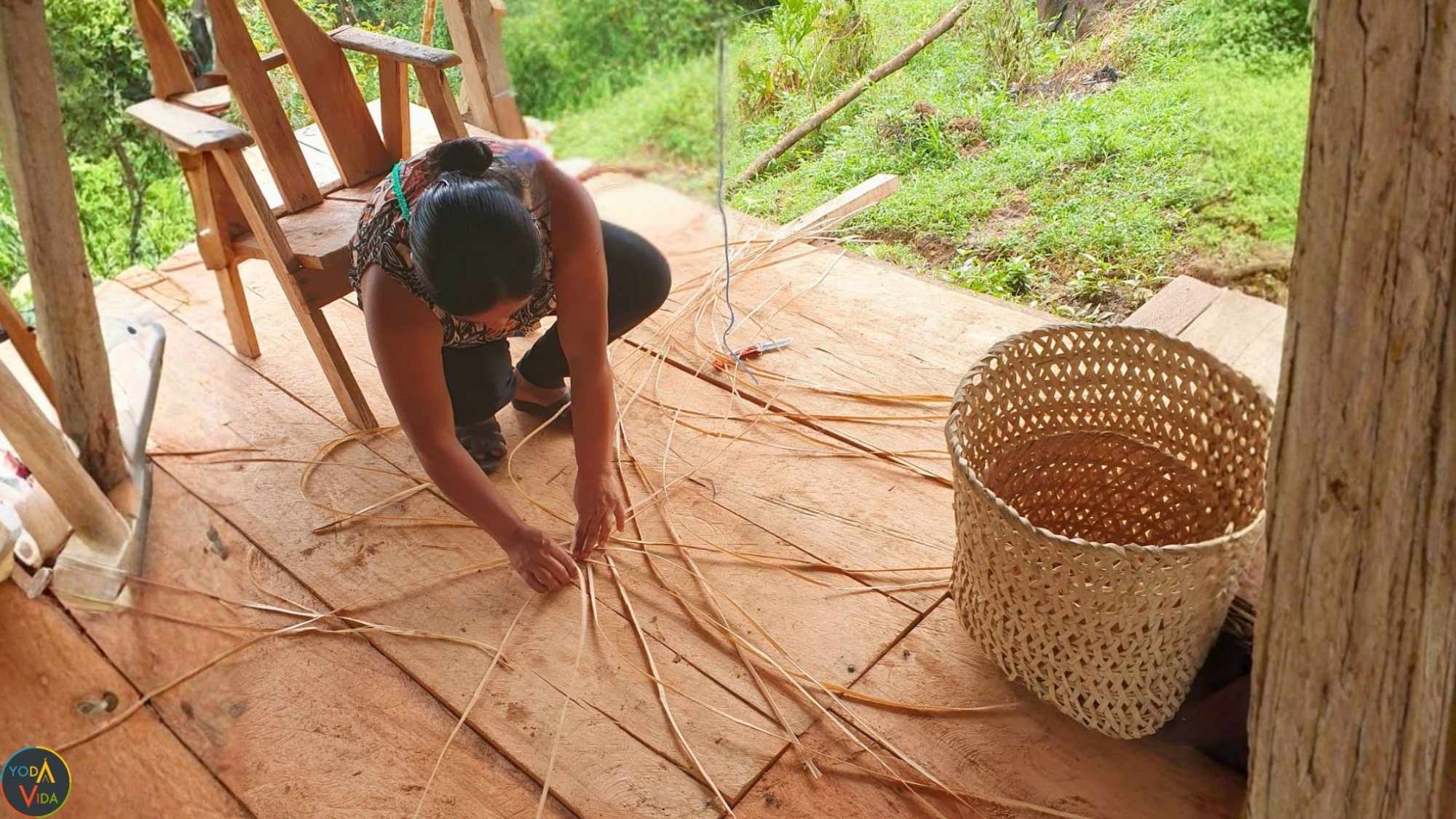 Indigenous woman weaving basket on porch